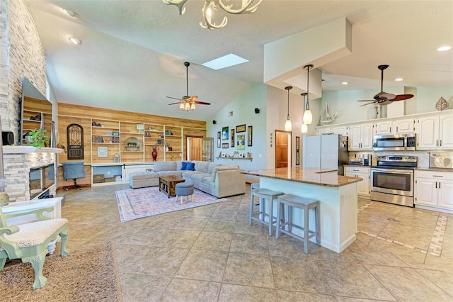 kitchen with appliances with stainless steel finishes, a kitchen breakfast bar, a skylight, dark stone counters, and white cabinets