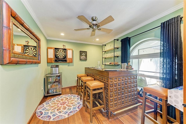 interior space with hardwood / wood-style floors, ceiling fan, crown molding, and bar