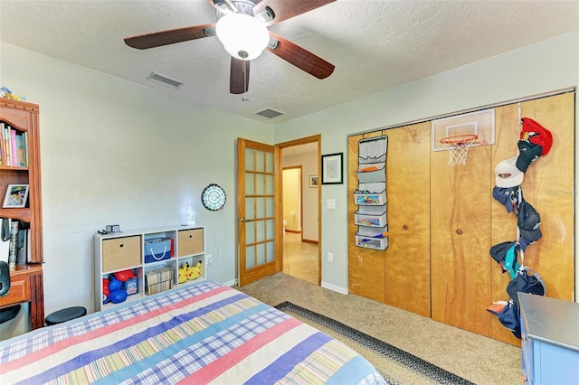 bedroom with ceiling fan, carpet floors, a textured ceiling, and a closet