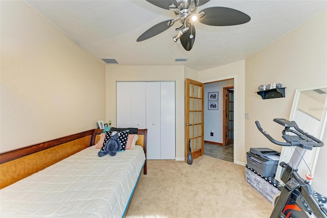 bedroom with light carpet, a textured ceiling, a closet, and ceiling fan