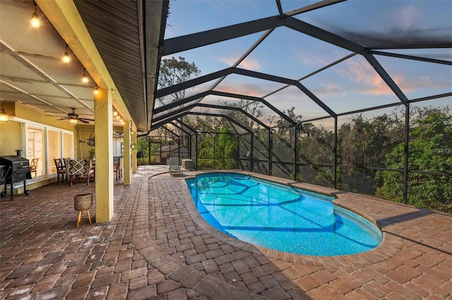 pool at dusk with ceiling fan, area for grilling, a lanai, and a patio