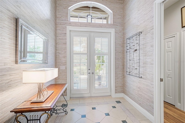 doorway to outside with light tile patterned floors, french doors, and a high ceiling