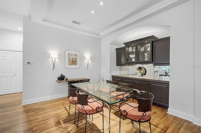 dining room featuring wood-type flooring, a tray ceiling, and crown molding