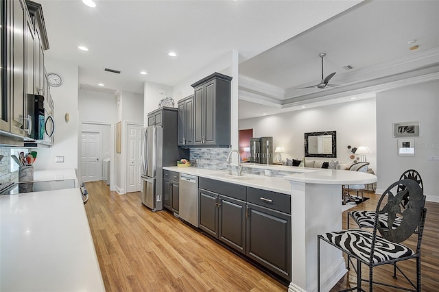 kitchen featuring a breakfast bar, sink, ceiling fan, kitchen peninsula, and stainless steel appliances