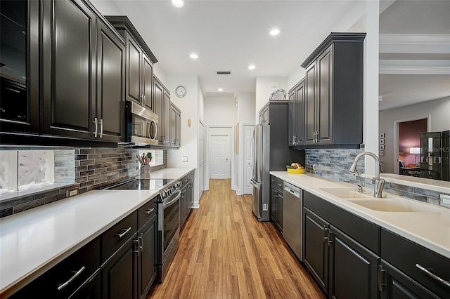 kitchen with backsplash, stainless steel appliances, light hardwood / wood-style flooring, and sink