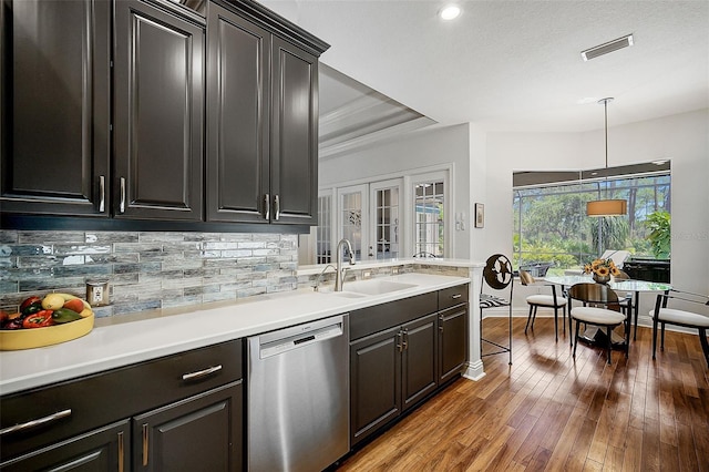 kitchen featuring dark hardwood / wood-style flooring, tasteful backsplash, stainless steel dishwasher, sink, and hanging light fixtures