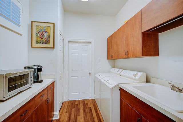 laundry area featuring light hardwood / wood-style floors, cabinets, independent washer and dryer, and sink