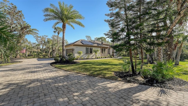 view of front of home featuring a front lawn, a garage, and solar panels