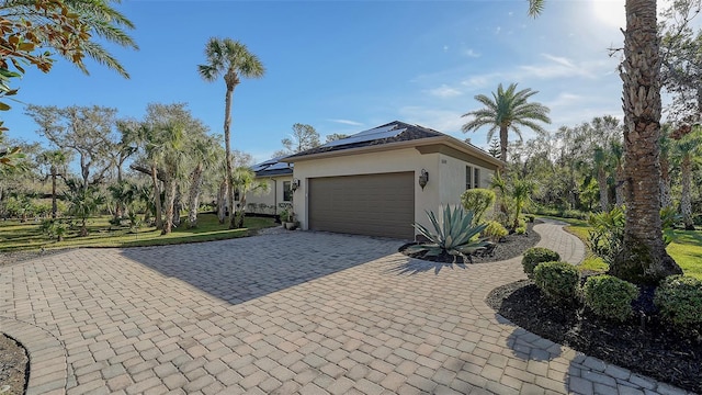 view of side of property featuring solar panels and a garage