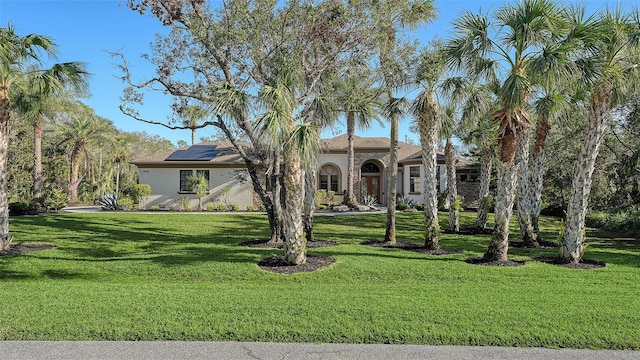 mediterranean / spanish-style house with a front yard and solar panels