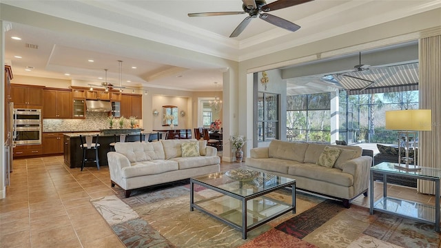 living room with light tile patterned floors, ceiling fan with notable chandelier, a raised ceiling, and crown molding