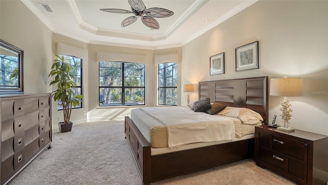 carpeted bedroom featuring a tray ceiling, ceiling fan, and ornamental molding