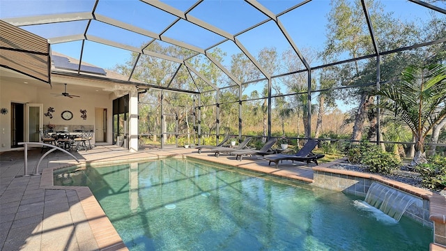 view of pool with a patio, pool water feature, glass enclosure, and ceiling fan