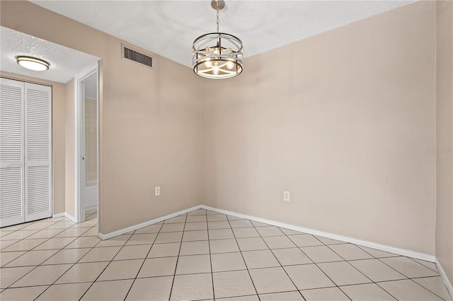 unfurnished room featuring a notable chandelier, light tile patterned flooring, and a textured ceiling