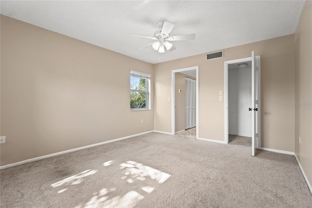 unfurnished bedroom featuring light carpet, a textured ceiling, a closet, and ceiling fan