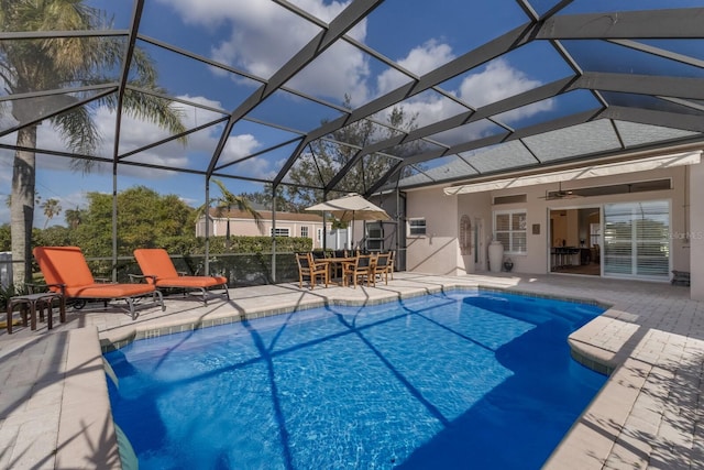 view of pool featuring glass enclosure, ceiling fan, and a patio