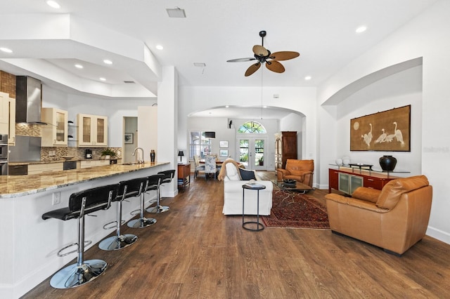 living room with ceiling fan, sink, and dark wood-type flooring