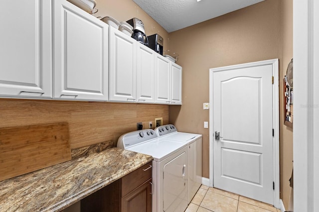 washroom with cabinets, light tile patterned floors, a textured ceiling, and separate washer and dryer