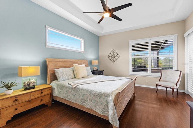 bedroom with a raised ceiling, ceiling fan, and dark wood-type flooring