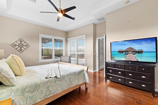 bedroom with a tray ceiling, ceiling fan, and dark wood-type flooring