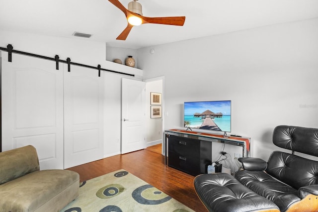 living room with a barn door, ceiling fan, and wood-type flooring