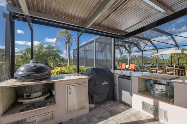 view of patio / terrace with a lanai, area for grilling, a bar, and exterior kitchen