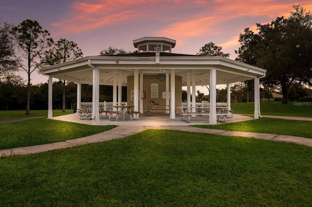 back house at dusk featuring a lawn and a gazebo