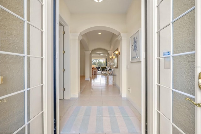 hall featuring light tile patterned floors and ornate columns