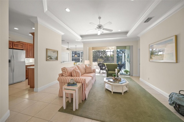 living room with a raised ceiling, ceiling fan, ornamental molding, and light tile patterned flooring