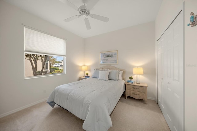 bedroom with ceiling fan, light carpet, and a closet