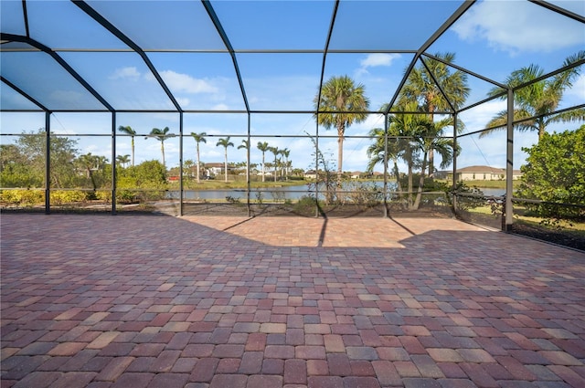 view of patio / terrace featuring glass enclosure and a water view