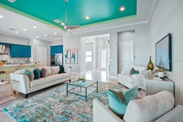 living room featuring ceiling fan, ornamental molding, and a tray ceiling