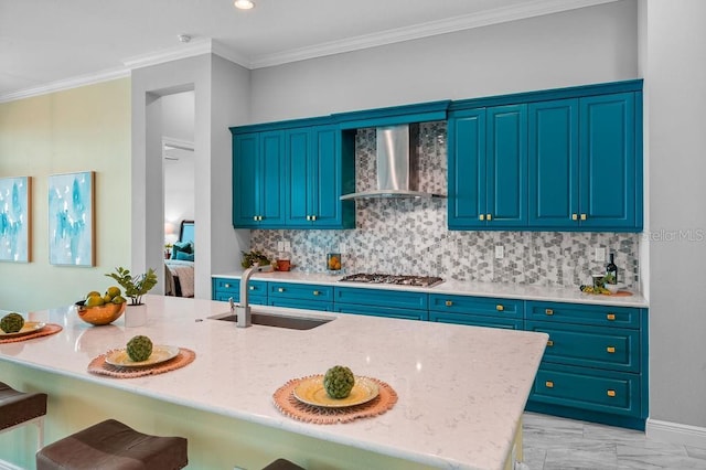 kitchen featuring wall chimney exhaust hood, sink, tasteful backsplash, and blue cabinets