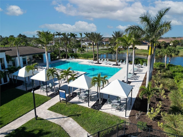 view of swimming pool with a water view, a lawn, and a patio area