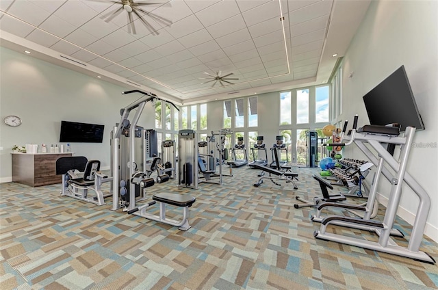 gym with ceiling fan, light carpet, and a towering ceiling