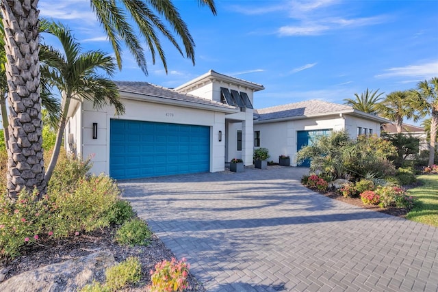 view of front of home with stucco siding, decorative driveway, and an attached garage