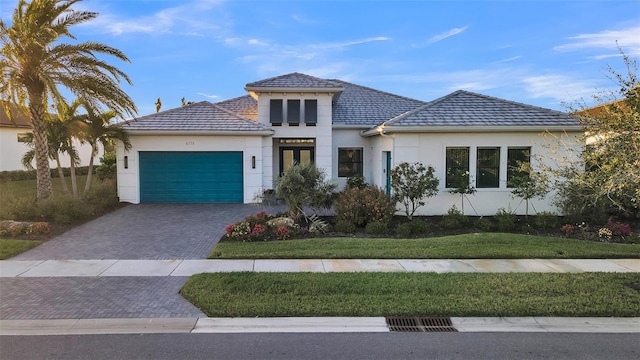 view of front of property featuring stucco siding, an attached garage, decorative driveway, and a front lawn