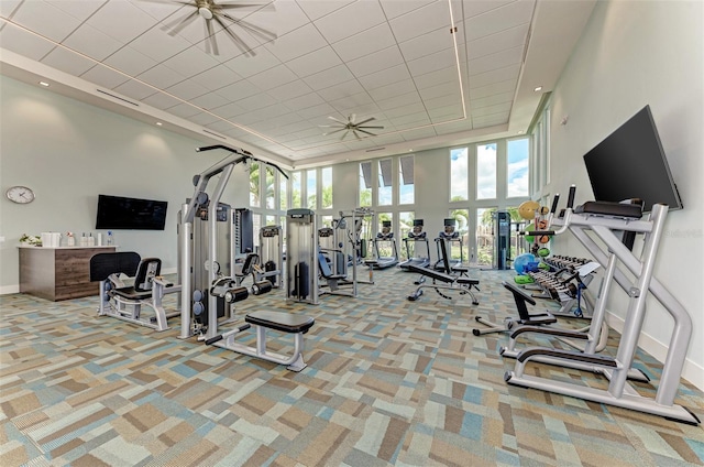workout area with a ceiling fan, a high ceiling, a healthy amount of sunlight, and carpet flooring