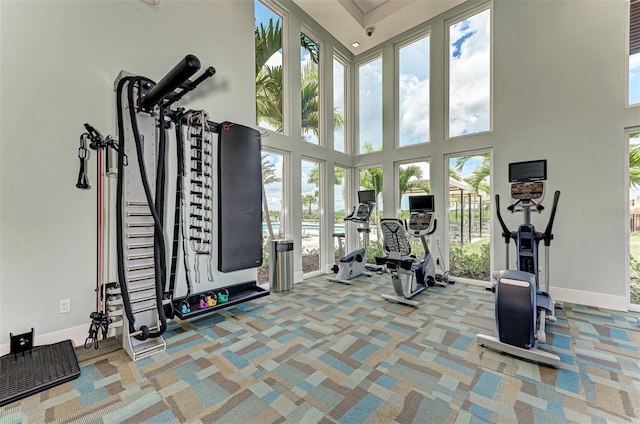 gym with carpet floors, a towering ceiling, and baseboards