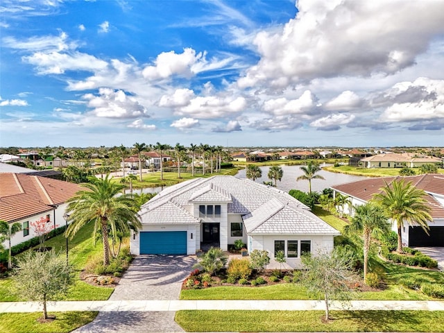 view of front facade featuring a tiled roof, a residential view, driveway, and a water view