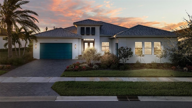 view of front of home with stucco siding, a front lawn, decorative driveway, and a garage