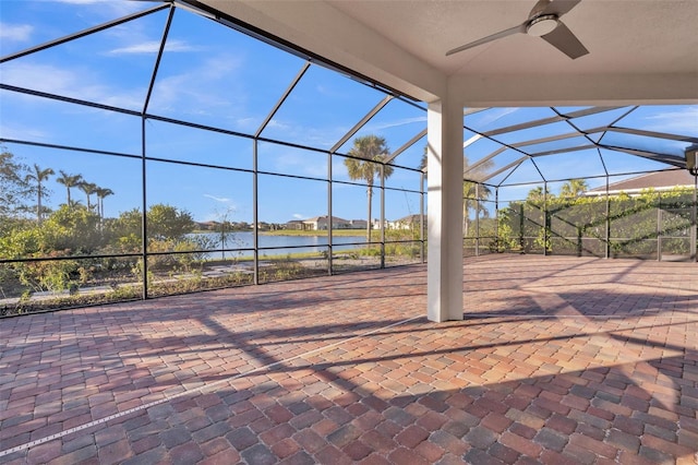 view of patio with a lanai, a ceiling fan, and a water view
