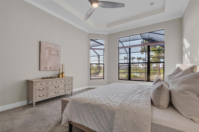carpeted bedroom with a tray ceiling, a ceiling fan, and baseboards