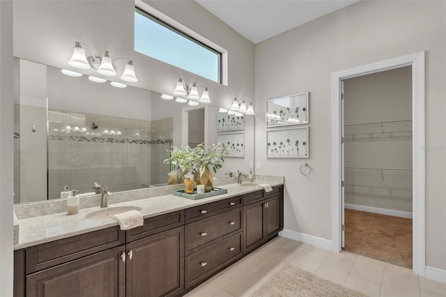 full bath featuring baseboards, a sink, double vanity, and tiled shower