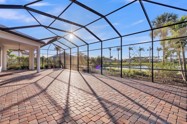 view of patio / terrace with glass enclosure, a water view, and ceiling fan