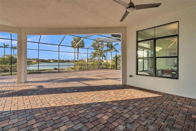 view of patio featuring ceiling fan, a lanai, and a water view