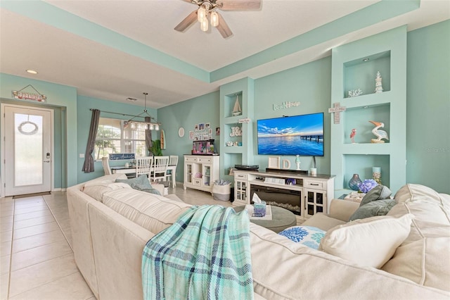 living room with built in shelves, light tile patterned floors, and ceiling fan