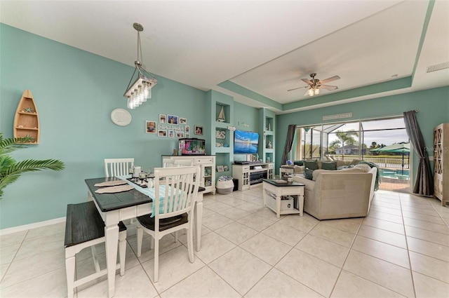 dining room with light tile patterned floors, a raised ceiling, ceiling fan, and built in shelves