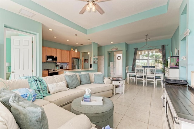 living room featuring ceiling fan, a raised ceiling, light tile patterned floors, and sink