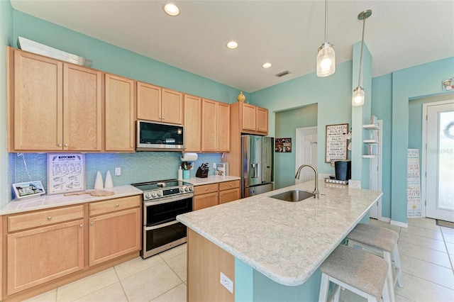 kitchen with decorative backsplash, appliances with stainless steel finishes, a kitchen island with sink, and sink